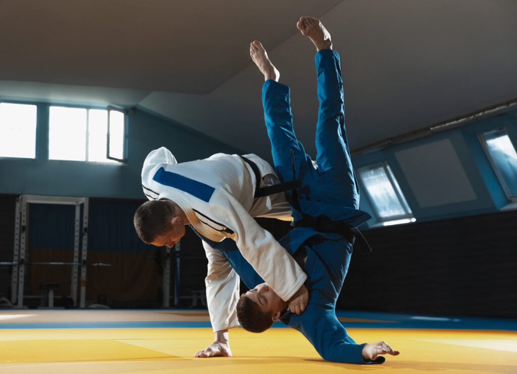 Two young judo fighters in kimono training martial arts in the gym with expression, in action and motion